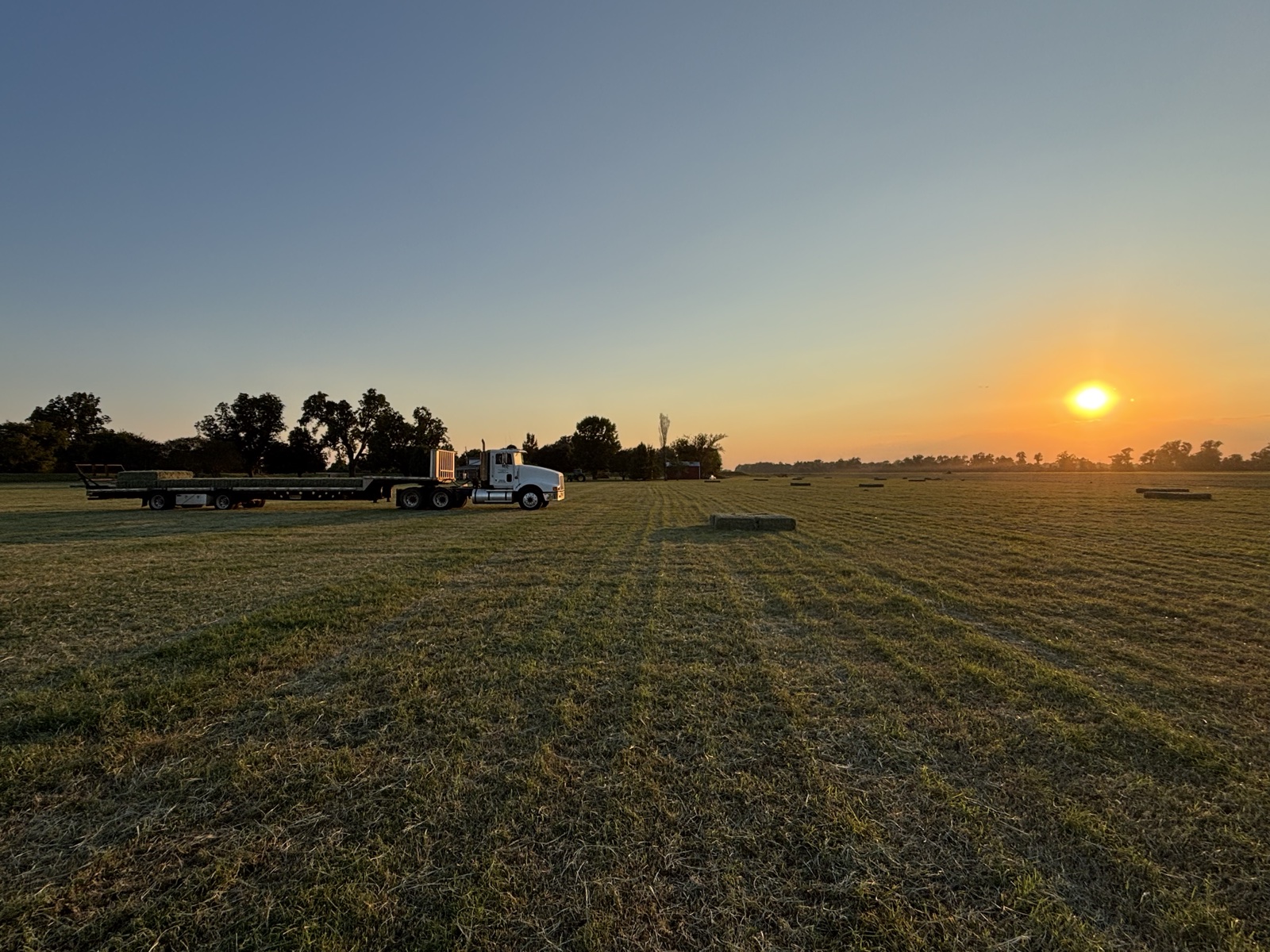 Flatbed truck in a hay field at sunset